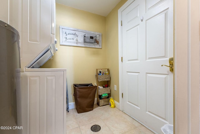 laundry area with stacked washer / drying machine and light tile patterned floors