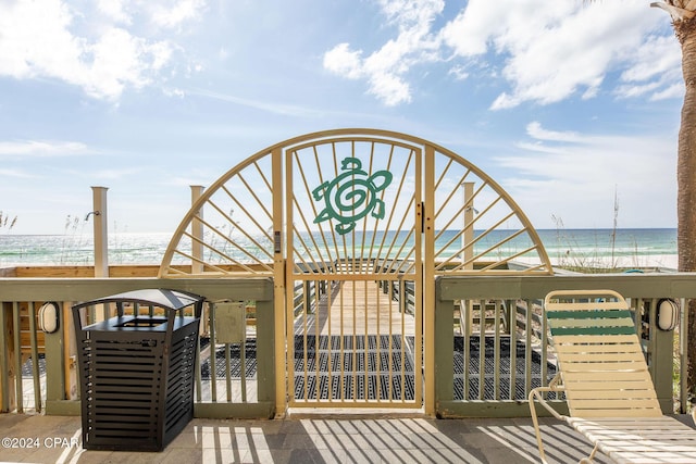 wooden terrace with a water view and a view of the beach