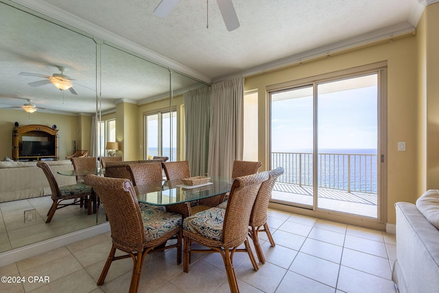 tiled dining area featuring ceiling fan, crown molding, a textured ceiling, and a water view