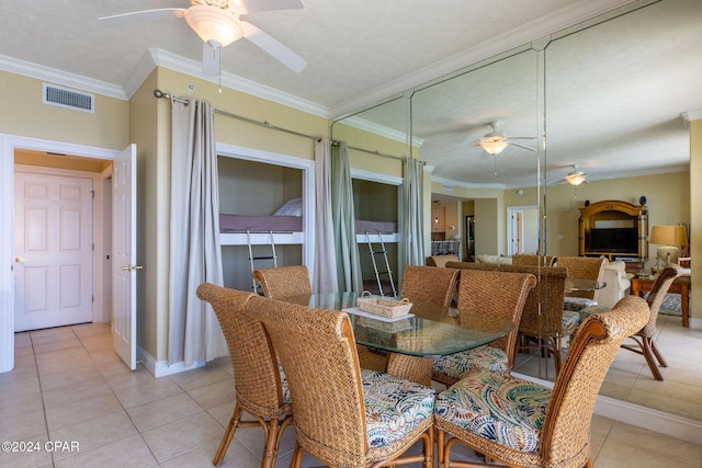 tiled dining area featuring ceiling fan, ornamental molding, and a textured ceiling