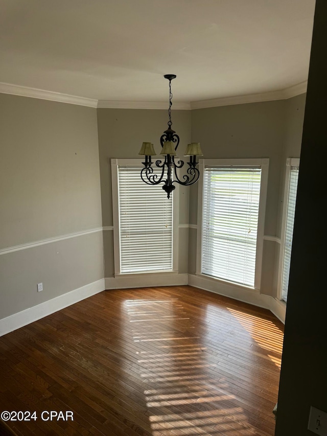 unfurnished dining area with dark hardwood / wood-style flooring, ornamental molding, and an inviting chandelier