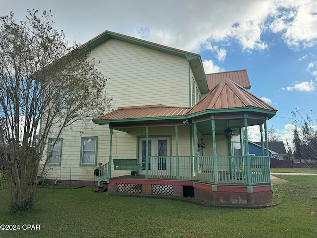 back of house featuring a yard, covered porch, and french doors