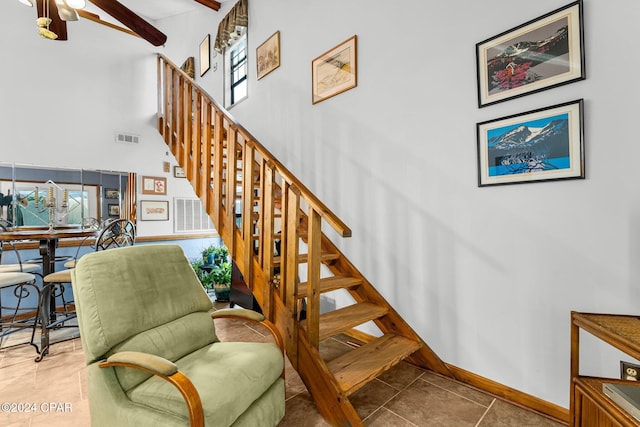 staircase with a towering ceiling and tile patterned floors