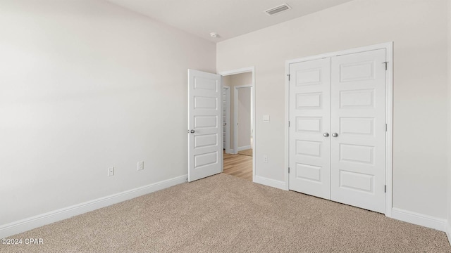 unfurnished bedroom with light colored carpet and a closet