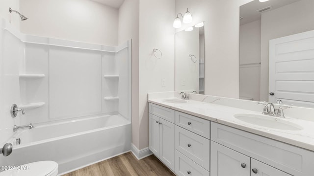 full bathroom featuring hardwood / wood-style flooring, washtub / shower combination, vanity, and toilet