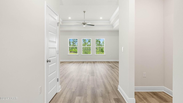 interior space with ornamental molding, light hardwood / wood-style floors, and a tray ceiling