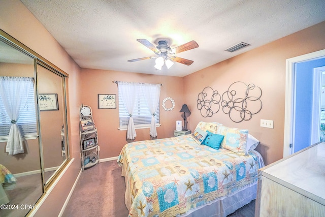 bedroom with dark colored carpet, ceiling fan, a textured ceiling, and a closet