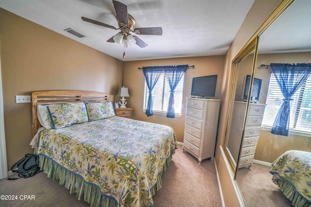 bedroom featuring light carpet, a closet, multiple windows, and ceiling fan