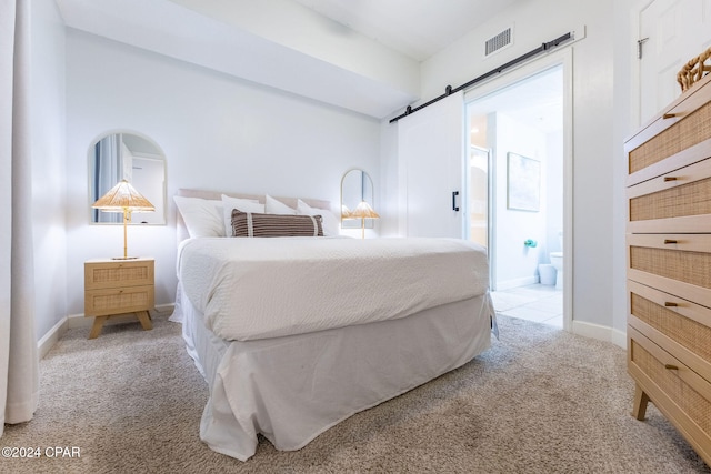 carpeted bedroom featuring connected bathroom and a barn door