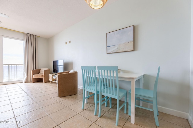 dining space with light tile patterned floors and lofted ceiling