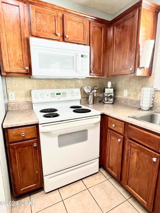 kitchen with decorative backsplash, sink, light tile patterned floors, and white appliances