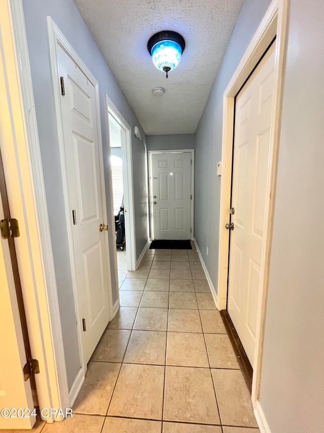 doorway to outside with light tile patterned floors and a textured ceiling