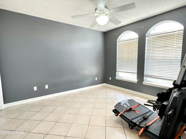 tiled spare room with a wealth of natural light, ceiling fan, and a textured ceiling