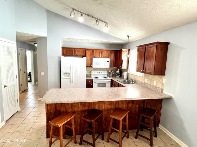 kitchen featuring sink, kitchen peninsula, pendant lighting, white appliances, and decorative backsplash