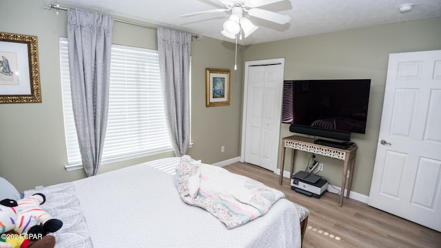 bedroom with hardwood / wood-style flooring, ceiling fan, a textured ceiling, and a closet