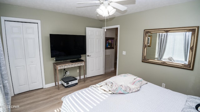 bedroom with ceiling fan, a closet, light hardwood / wood-style floors, and a textured ceiling