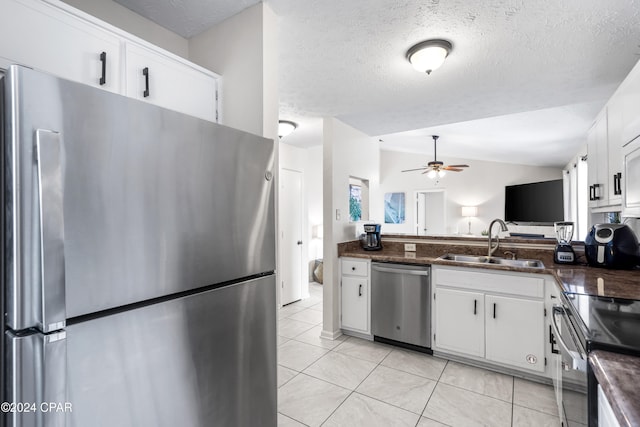 kitchen featuring stainless steel appliances, vaulted ceiling, ceiling fan, sink, and white cabinetry