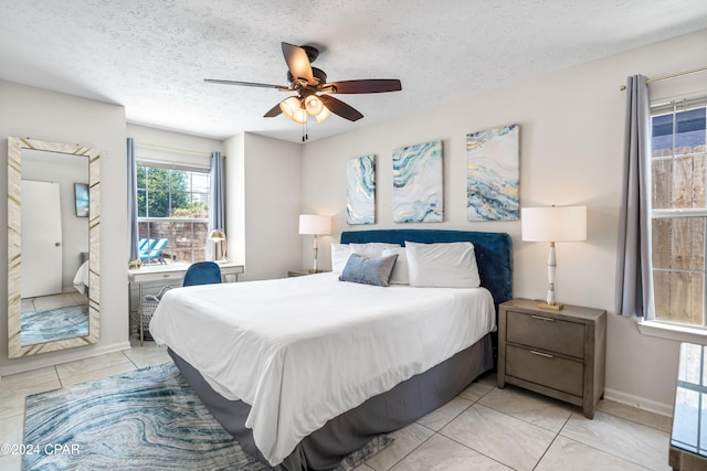 tiled bedroom with ceiling fan and a textured ceiling