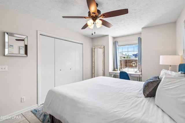 bedroom with light tile patterned floors, a textured ceiling, a closet, and ceiling fan