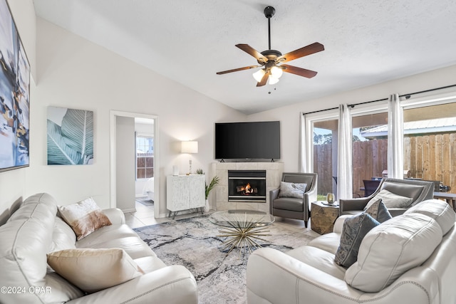 tiled living room featuring a fireplace, ceiling fan, plenty of natural light, and lofted ceiling