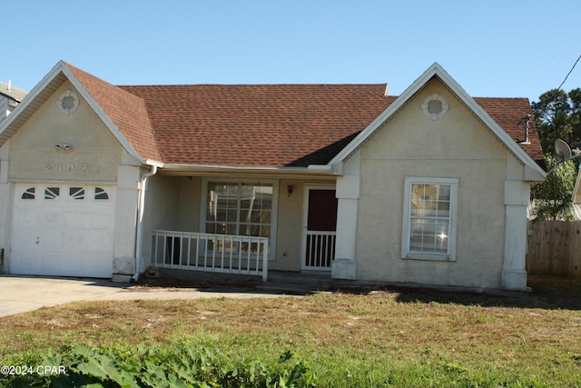 view of front of home featuring a garage, covered porch, and a front yard