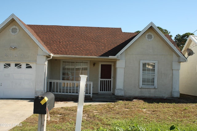 ranch-style house with a porch, a garage, and a front lawn