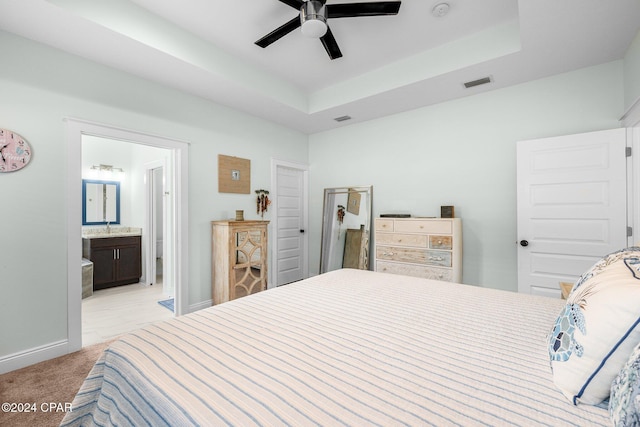 carpeted bedroom featuring ensuite bathroom, a raised ceiling, ceiling fan, and sink