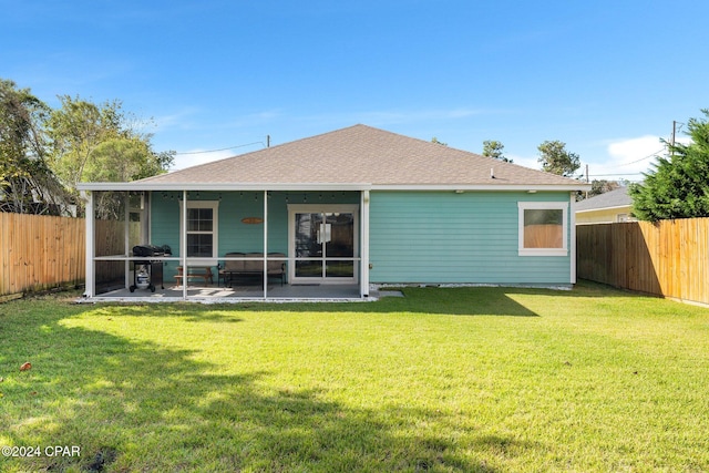 back of property with a yard, a patio, and a sunroom