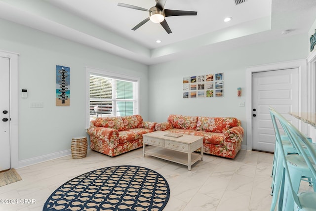 living room featuring a tray ceiling and ceiling fan