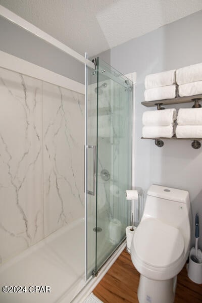 bathroom featuring hardwood / wood-style flooring, toilet, walk in shower, and a textured ceiling