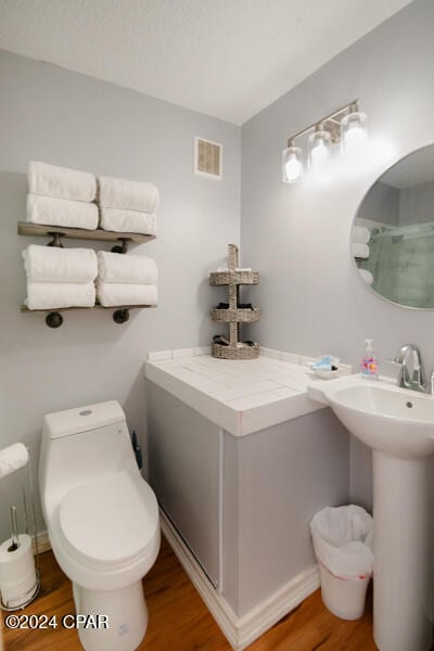 bathroom with hardwood / wood-style floors, toilet, and sink