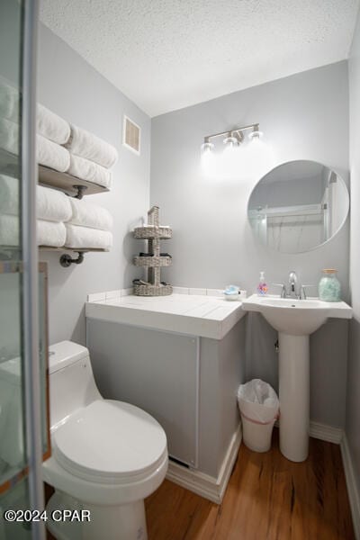 bathroom with a textured ceiling, hardwood / wood-style flooring, and toilet