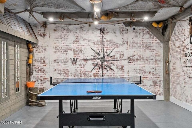 playroom featuring concrete floors and brick wall