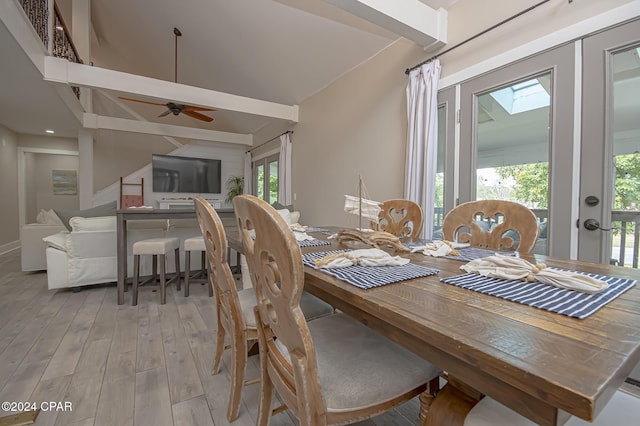 dining area featuring light wood-type flooring, vaulted ceiling with beams, and a ceiling fan