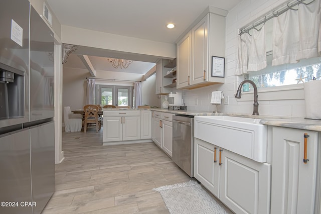 kitchen with visible vents, appliances with stainless steel finishes, a peninsula, light wood-style floors, and backsplash