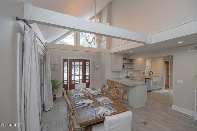 dining area with high vaulted ceiling, visible vents, baseboards, light wood-style floors, and an inviting chandelier