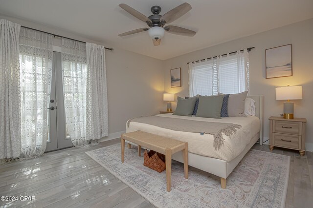 bedroom with light wood-style floors, french doors, multiple windows, and ceiling fan