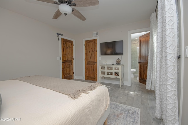 bedroom featuring a ceiling fan, light wood-type flooring, visible vents, and ensuite bath