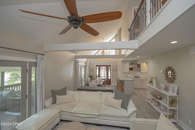 living area featuring ceiling fan, a high ceiling, visible vents, baseboards, and light wood-type flooring