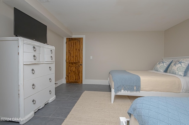 bedroom with dark tile patterned floors and baseboards