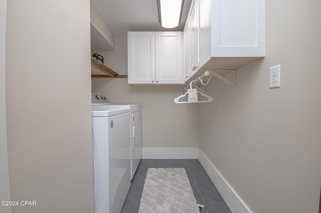 laundry area with cabinet space, washer and clothes dryer, baseboards, and dark tile patterned floors