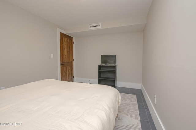 bedroom with dark tile patterned flooring, visible vents, and baseboards