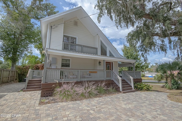 view of front of house with a porch, fence, and a balcony