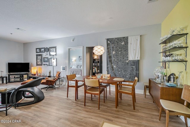 dining space with light wood-type flooring and a textured ceiling