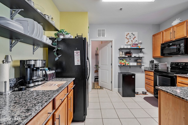 kitchen with dark stone counters, light tile patterned flooring, black appliances, and a textured ceiling