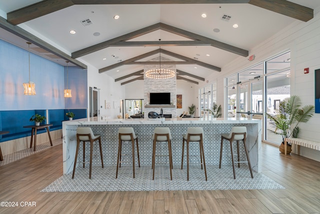 kitchen with a chandelier, a kitchen breakfast bar, light wood-type flooring, and lofted ceiling with beams