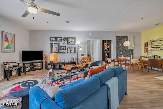 living room featuring ceiling fan, light hardwood / wood-style floors, and a textured ceiling