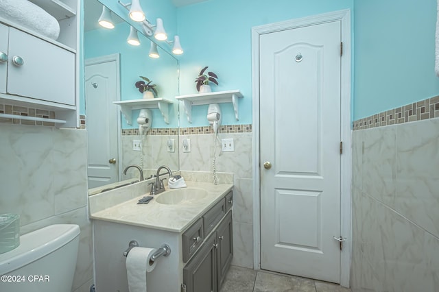 bathroom with tile patterned flooring, vanity, toilet, and tile walls