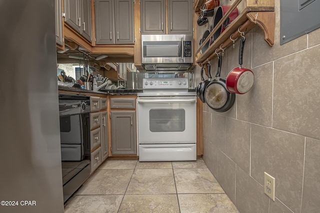 kitchen featuring gray cabinets, light tile patterned floors, tile walls, and appliances with stainless steel finishes