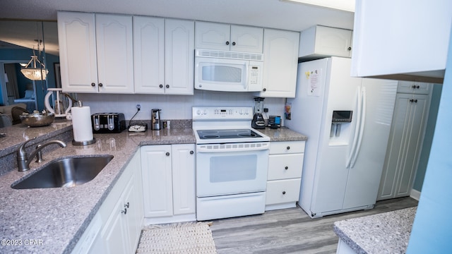 kitchen featuring white cabinetry, sink, white appliances, and light hardwood / wood-style flooring